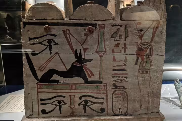 Painted wooden sarcophagus panel with Eye of Horus and Anubis at Luxor Mummification Museum half-day tour