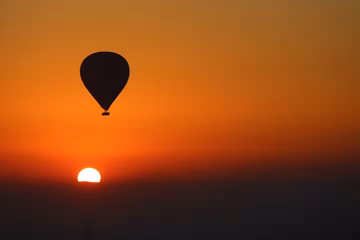 Silhouette hot air balloon at sunrise over Luxor, Egypt, scenic Nile River Valley flight with golden desert horizon