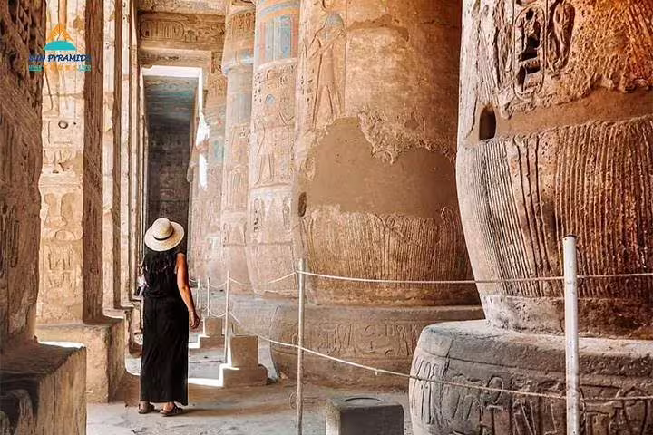 Traveler in Luxor temple corridor with ancient carvings, highlight of 12-day Cairo Luxor Aswan Petra tour