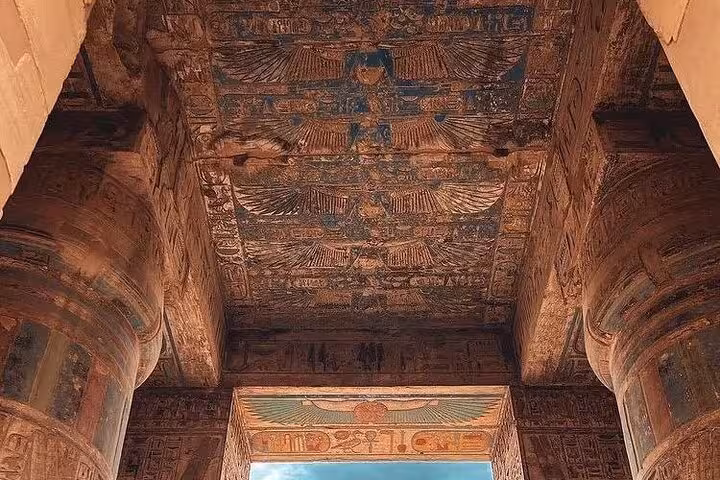 Painted ceiling and massive columns inside an ancient Luxor temple, included in 8-day Egypt tour Cairo Aswan Abu Simbel