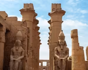 Colossal seated pharaoh statues and massive columns at Luxor Temple, Egypt