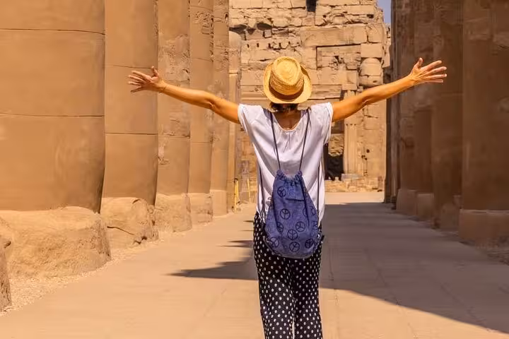 Visitor walking between Luxor Temple columns on Cairo to Luxor by plane small group tour with guide