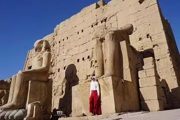 Traveler by colossal statues at Luxor Temple, Egypt, included in a 3-day Luxor city break package
