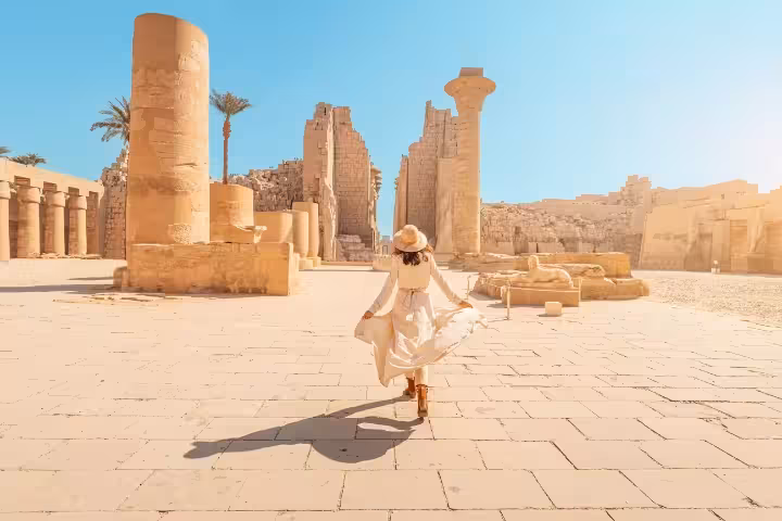 Traveler exploring Luxor Temple ruins under blue sky, part of a 7-day Egypt comfort Nile cruise and temples tour