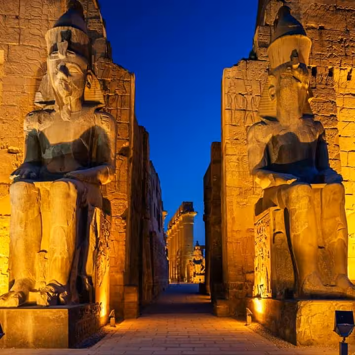 Stunning view of Luxor Temple entrance with illuminated colossal pharaoh statues, perfect for Nile Valley adventures.