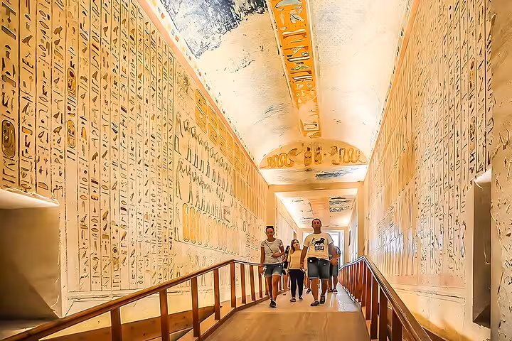 Travelers explore a hieroglyph-lined Luxor temple corridor on small-group Cairo to Luxor flight tour