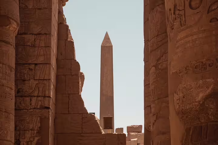 Luxor Temple obelisk framed by carved sandstone columns on a private Cairo to Luxor flight tour