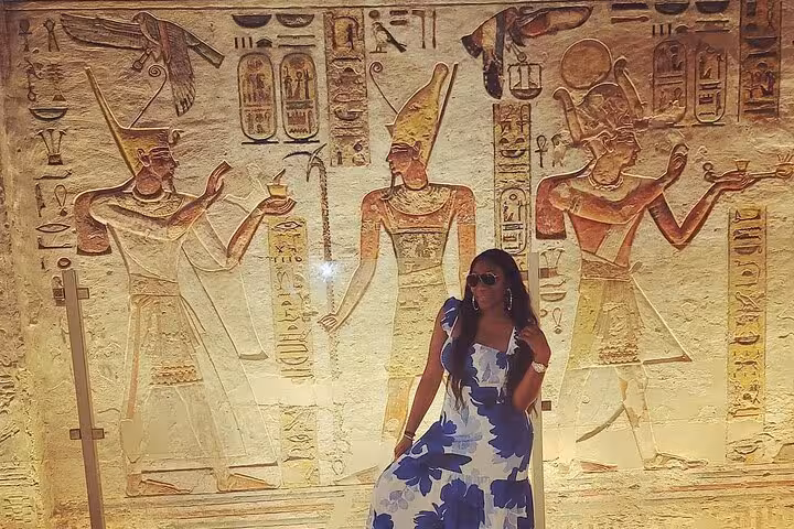Traveler posing by ancient Egyptian wall carvings in a Luxor tomb, part of private 10-day Nile cruise itinerary