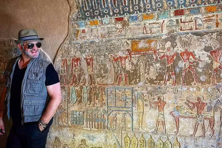 Traveler viewing colorful tomb wall paintings in Luxor, part of overnight Aswan to Luxor tour via Edfu and Kom Ombo