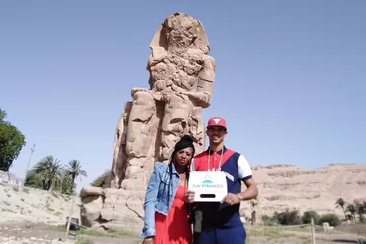 Travelers pose by the Colossi of Memnon on a private full-day Luxor tour from Aswan by car, Egypt