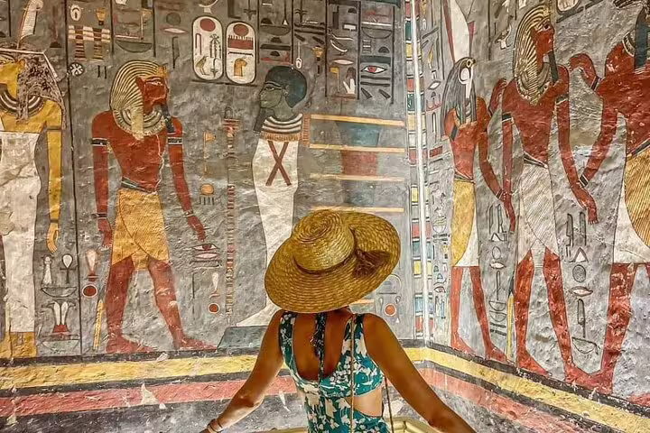 Traveler viewing colorful tomb wall paintings in Luxor Valley of the Kings on private Cairo sleeper train trip