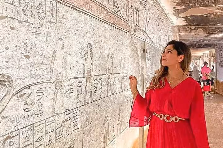 Tourist admiring detailed hieroglyphics at Luxor's West Bank, showcasing ancient Egyptian art and history.