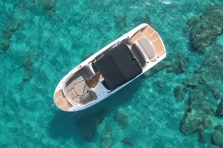 Aerial view of a luxury boat floating on crystal-clear turquoise waters near Cala Bassa, ideal for premium tours.