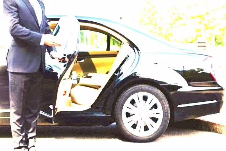 Chauffeur apre la portiera di un’auto di lusso nera per transfer privato da Napoli a Praiano con servizio professionale