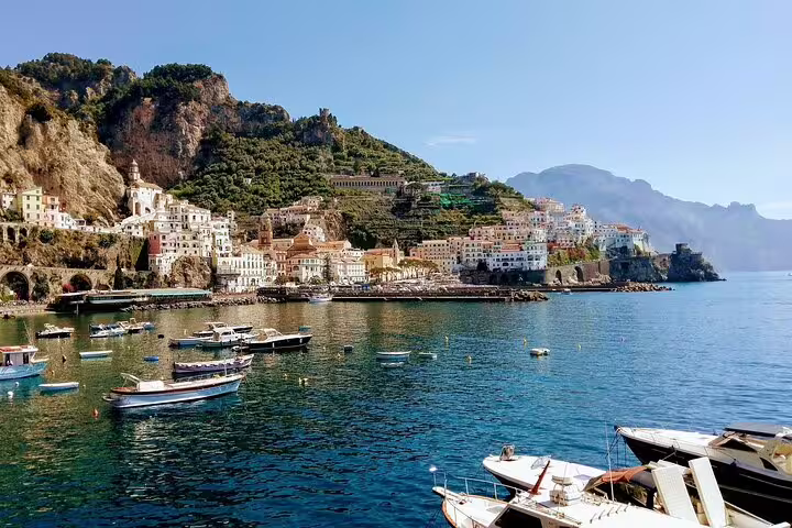 Colorful cliffside village and small boats anchored in a calm bay, seen from a luxury Amalfi Coast weekly catamaran cruise