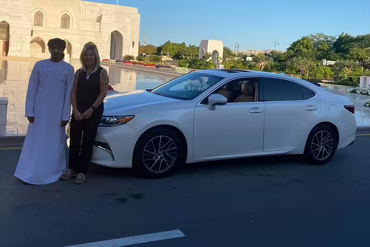 Chauffeur-driven white Lexus in Muscat with passengers, showcasing luxury travel experience in Oman.