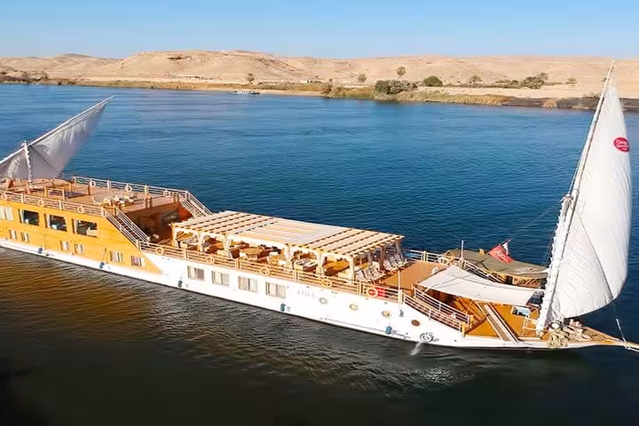 Luxury dahabiya Nile cruise boat with sun deck sailing past desert shores on a 5 days 4 nights Egypt itinerary