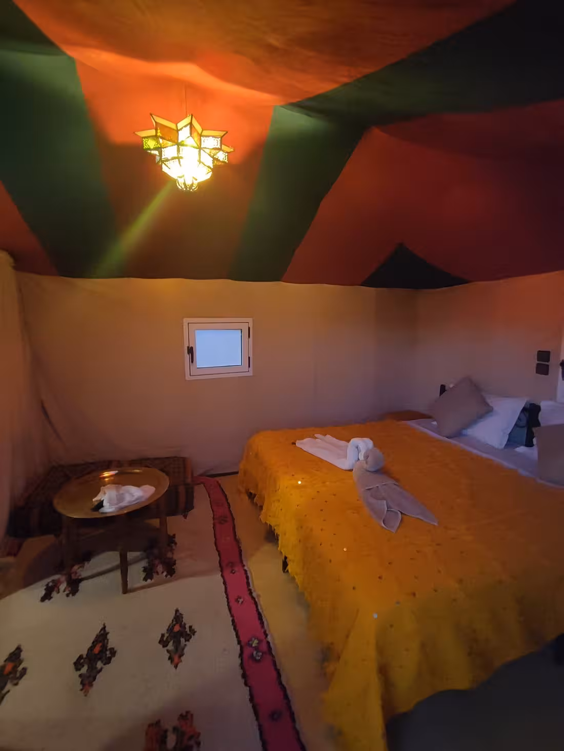 Elegant interior of a luxury desert tent with colorful decor and ambient lighting in Merzouga Erg Chebbi.