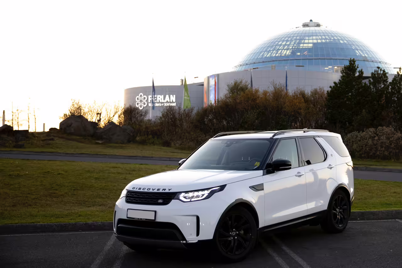 Luxury Land Rover Discovery SUV parked near Perlan museum for private transfer service in Reykjavik Iceland