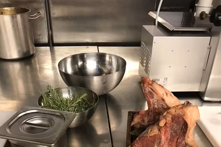 Luxurious cooking class showcases premium raw meat and fresh rosemary on a wooden board in a modern kitchen setup.