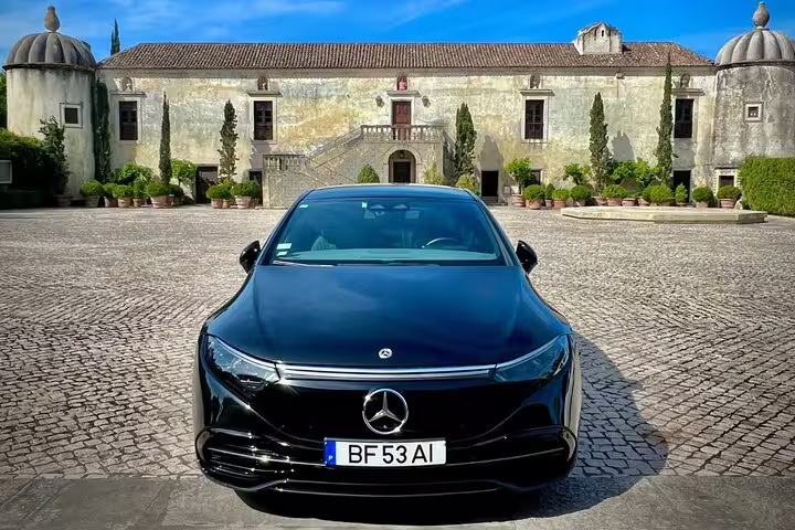 Luxury Mercedes parked in front of historic estate for Porto to Lisbon private journey, offering direct routes or custom stops.