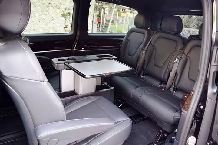 Spacious luxury minivan interior with leather seats and table used for private transfer from Rome to Positano, Italy
