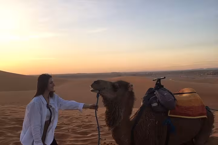 Traveler enjoying a sunset with a camel on the Morocco desert tour from Fes, highlighting the tour's luxury experience.