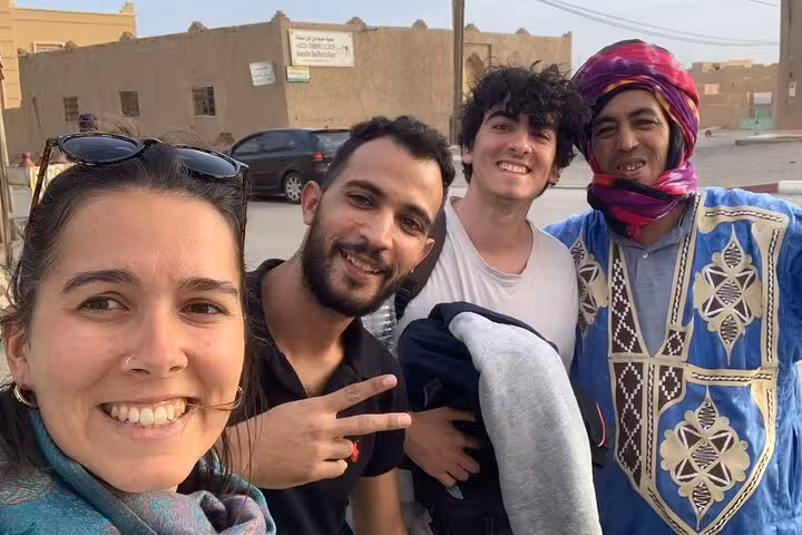 Travelers enjoying a friendly moment with a local guide in a Moroccan village on a luxury desert tour from Fes.