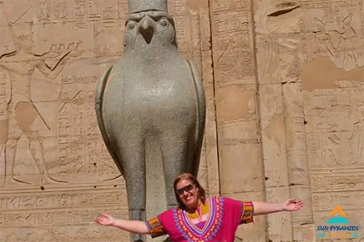 Guest at Horus falcon statue and temple carvings on Nile cruise excursion, Luxury 8-day Cairo and Oberoi Philae tour