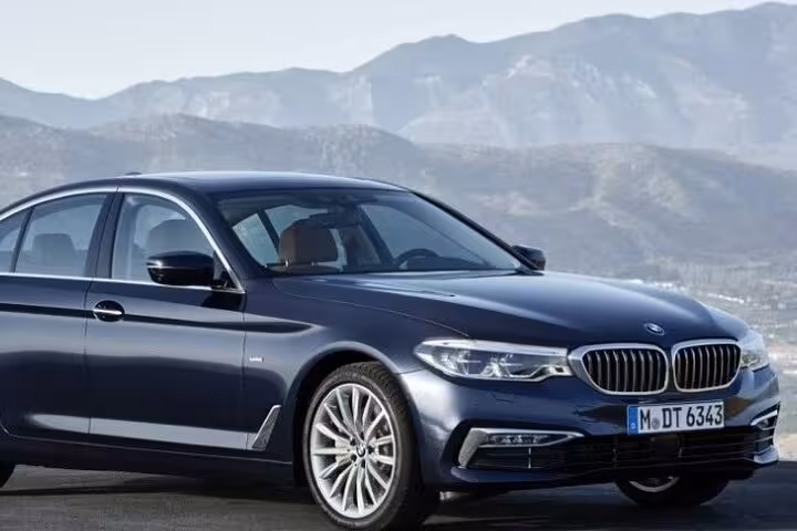 Luxury car ready for private transfer from Fiumicino Airport to Rome with scenic mountain backdrop.