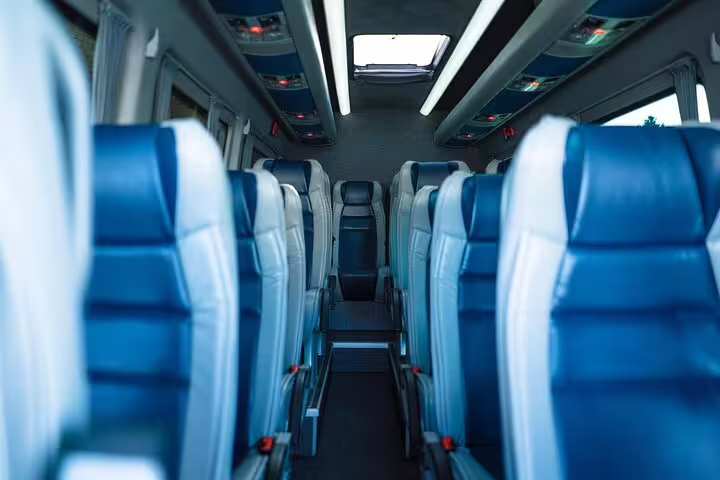 Luxury private transfer interior with blue leather seats and central aisle in a premium coach