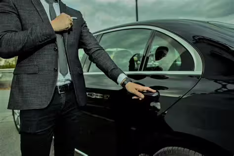 Professional chauffeur in suit opening luxury black sedan door for private transfer between Naples and Salerno Vietri sul Mare