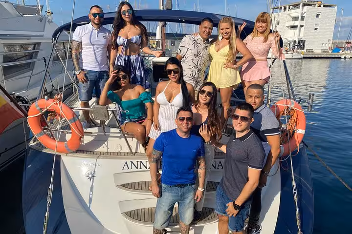 Friends posing on a luxury sailboat in Barcelona marina on a private sailing tour for up to 12 guests