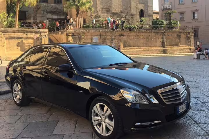 Luxury black sedan used for private transfer between Hotel Mercure Palermo Centro and Palermo Airport parked in historic city center