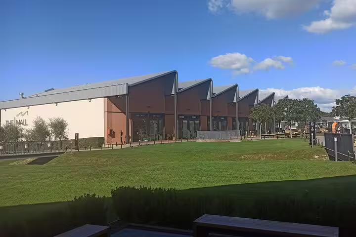 Modern open-air The Mall Firenze luxury outlets with green lawns, ideal stop on private chauffeur shopping tour in Tuscany