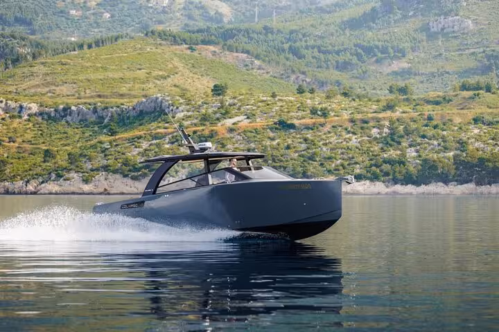 Luxury private speedboat tour in Croatia cruising calm Adriatic waters with scenic green coastline backdrop