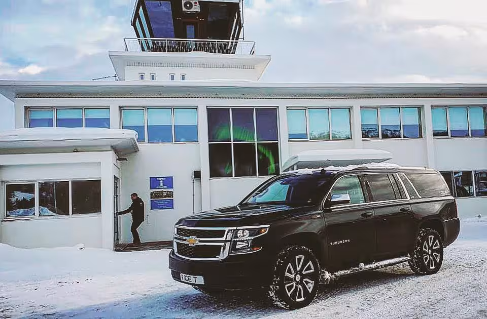 Black Chevrolet Suburban luxury SUV parked outside Akureyri Airport terminal in snowy Iceland