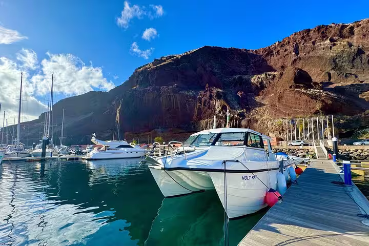 Luxurious boat docked at a picturesque marina with stunning cliff views, ideal for private sunset cruises.
