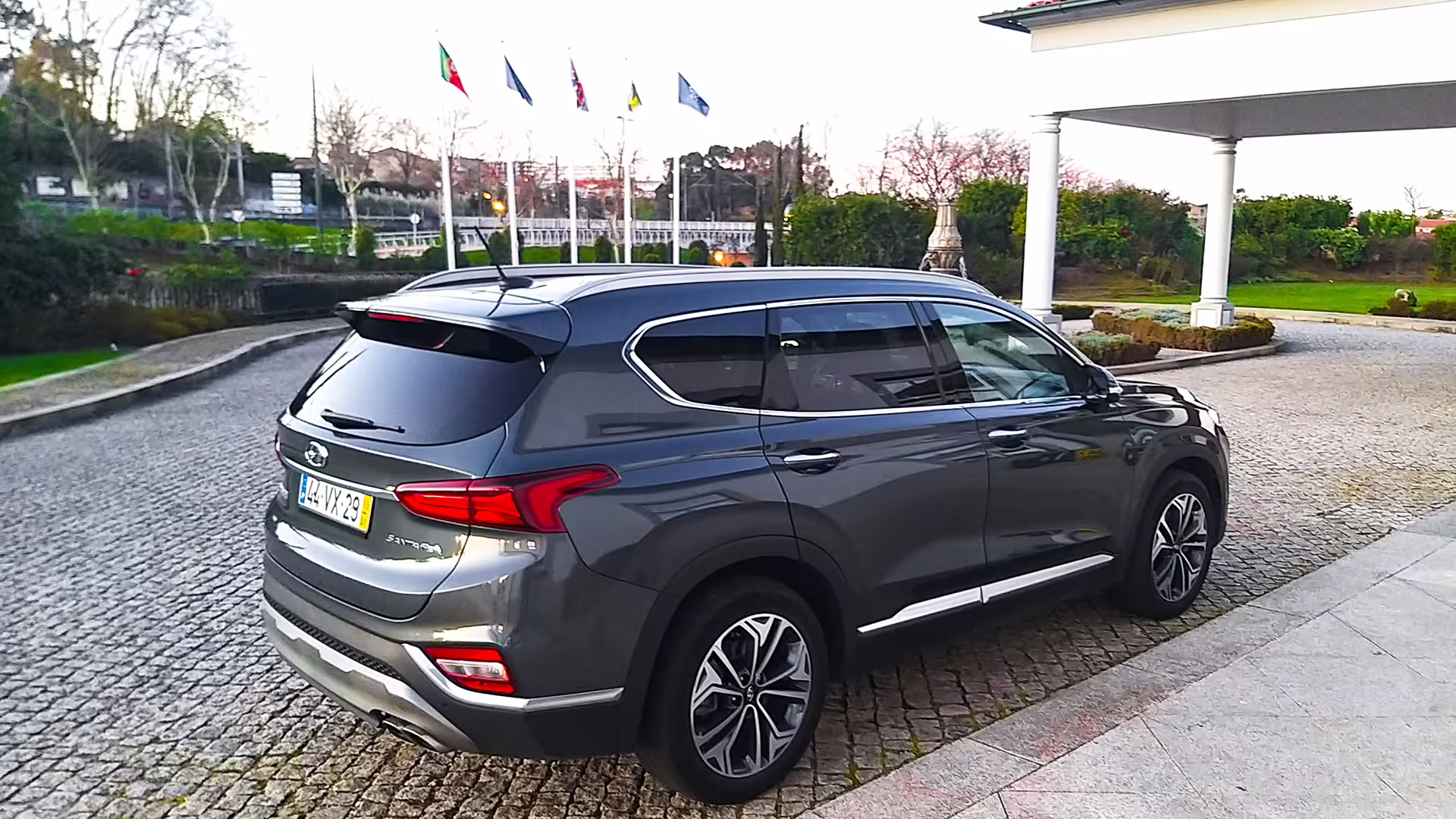 Luxury SUV ready for private transfer from Porto to Vila Real, parked near a scenic location with flags waving.