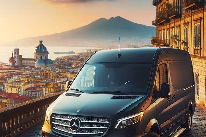 Luxury tour van parked with stunning view of Naples cityscape and Mount Vesuvius at sunset, ideal for Pompeii excursions.