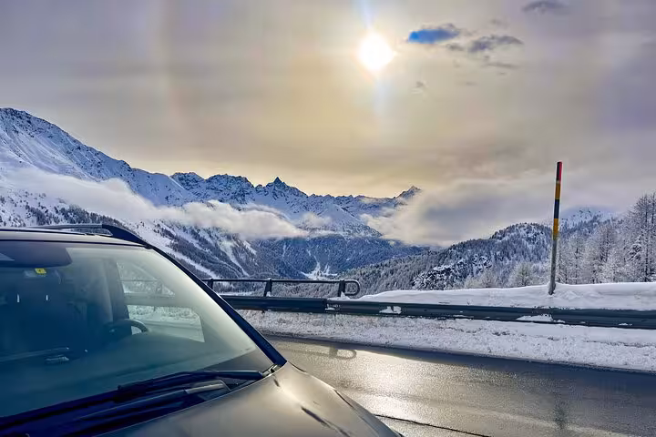 Sleek car on a scenic snowy mountain road with breathtaking views, capturing the luxury transfer from Milan to St. Moritz.