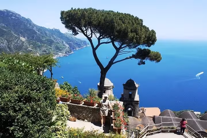 Silver luxury van on coastal road with stunning Positano backdrop, ideal for Amalfi Coast day tours.