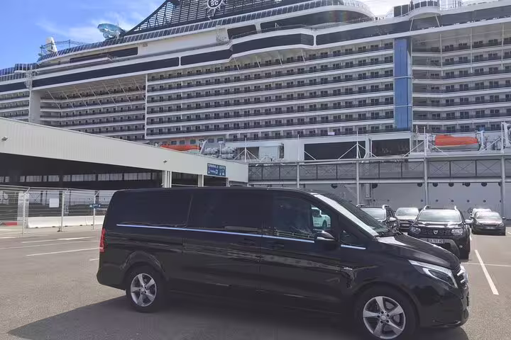 Black luxury Mercedes van parked at Marseille cruise port with large cruise ship in background