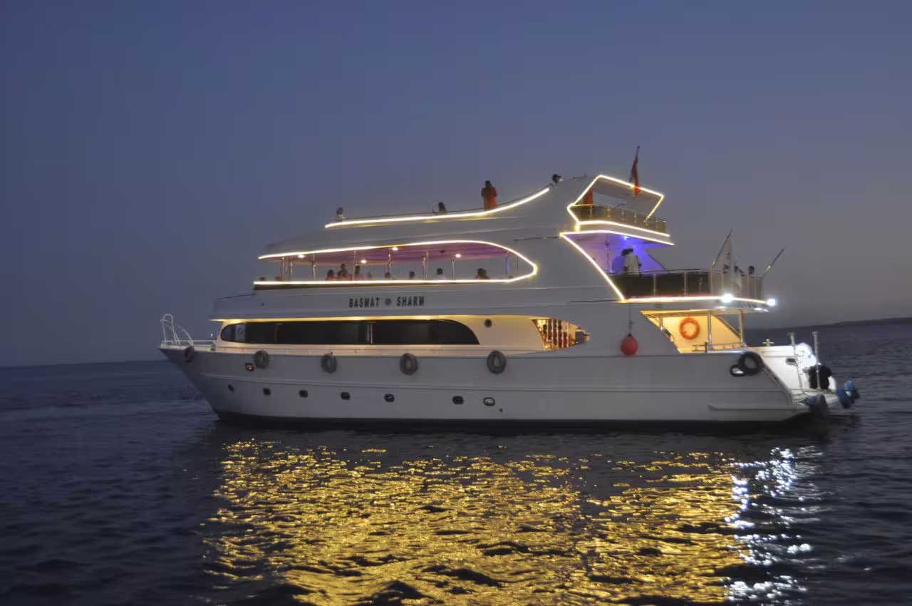 Luxury VIP yacht lit at dusk on Red Sea, Sharm El Sheikh dinner cruise with onboard dining and views