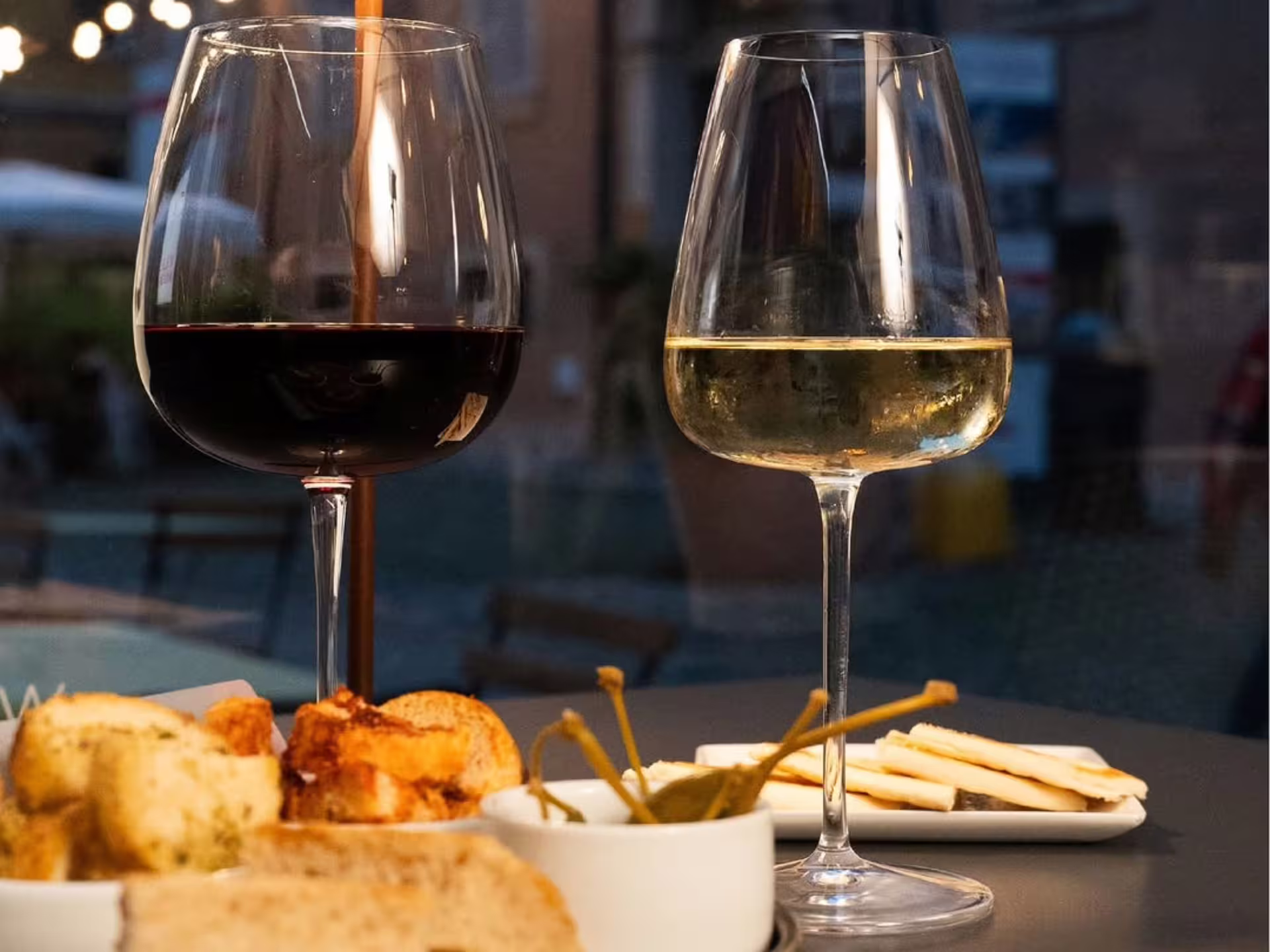 Two wine glasses with local snacks on table, Modena city center luxury wine tasting tour aperitivo