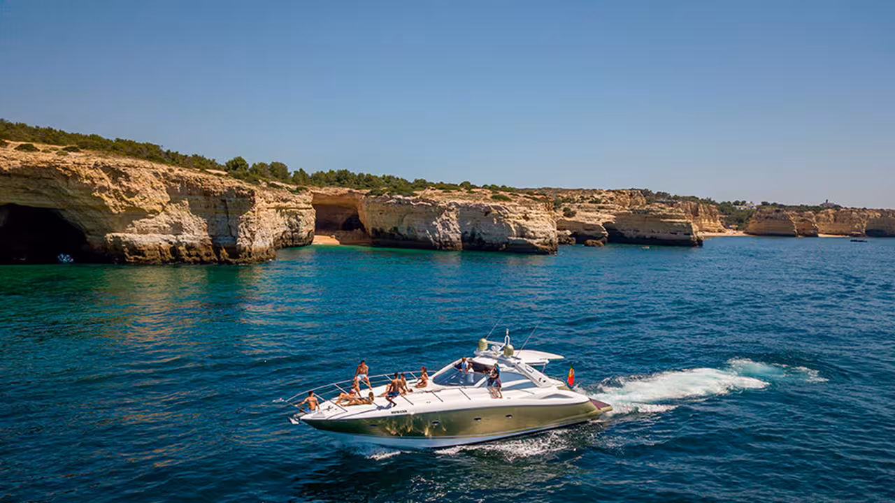 Luxury yacht cruising turquoise Algarve waters past sea caves and cliffs on Full Day Cruise Gold 10 hours