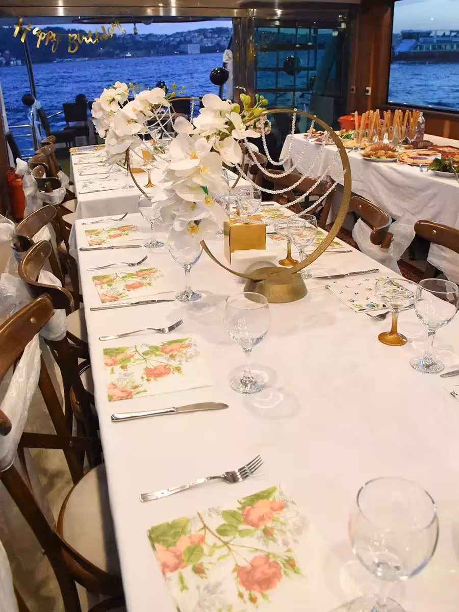 Luxury yacht birthday dinner table with floral decor, place settings, and sea views for private celebration cruise