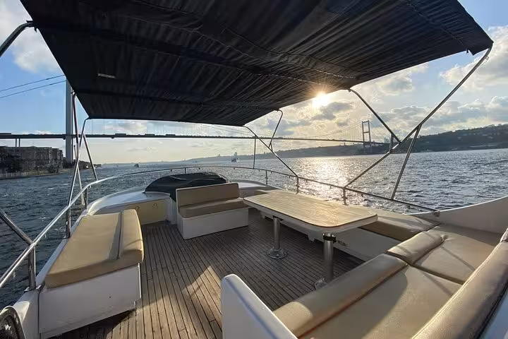 Spacious luxury yacht seating with table on Istanbul Bosphorus sunset cruise, view of Bosphorus Bridge