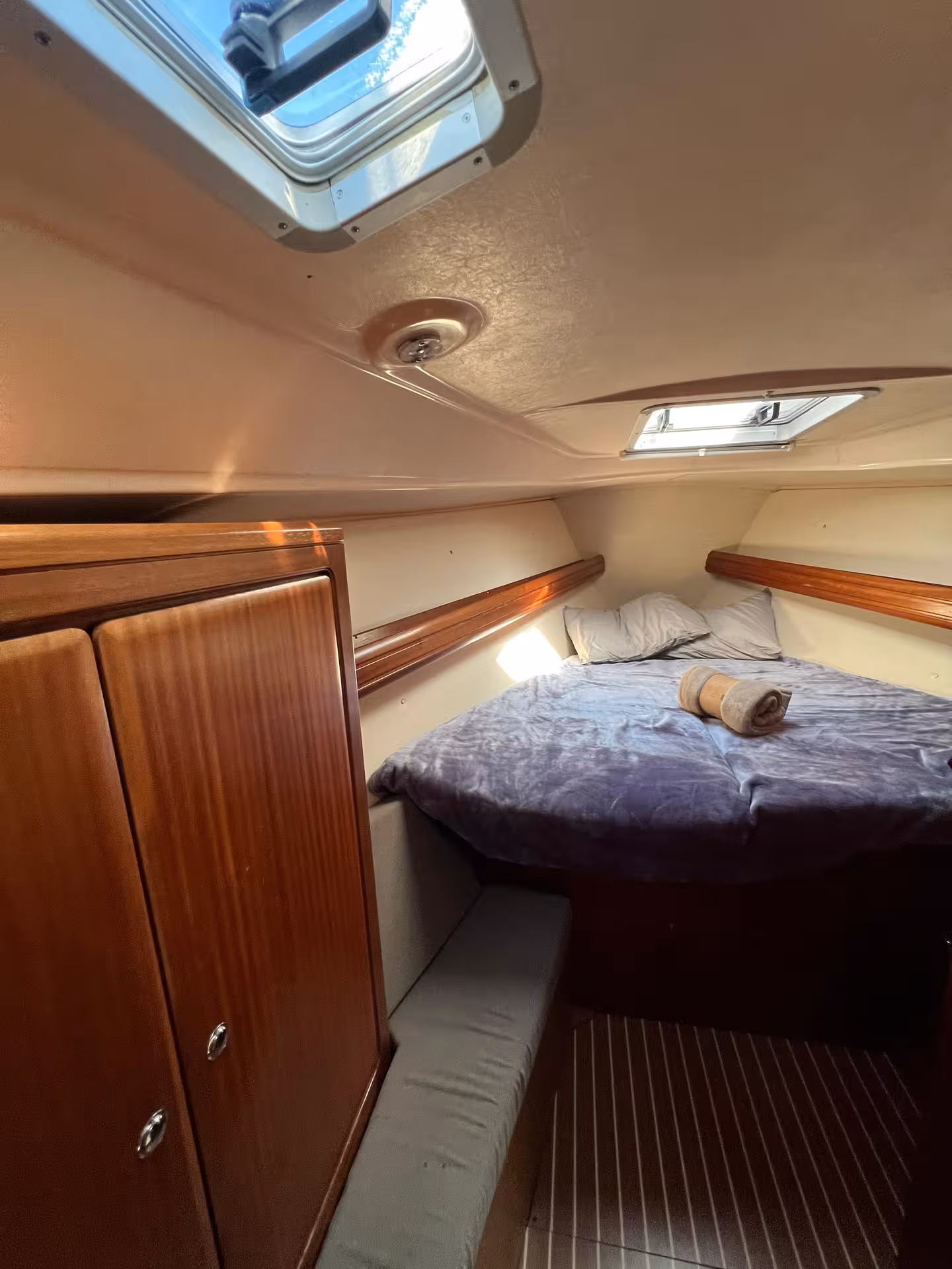 Cozy yacht cabin double bed with skylight and wood trim, ideal for Lagos sunrise luxury yacht cruise