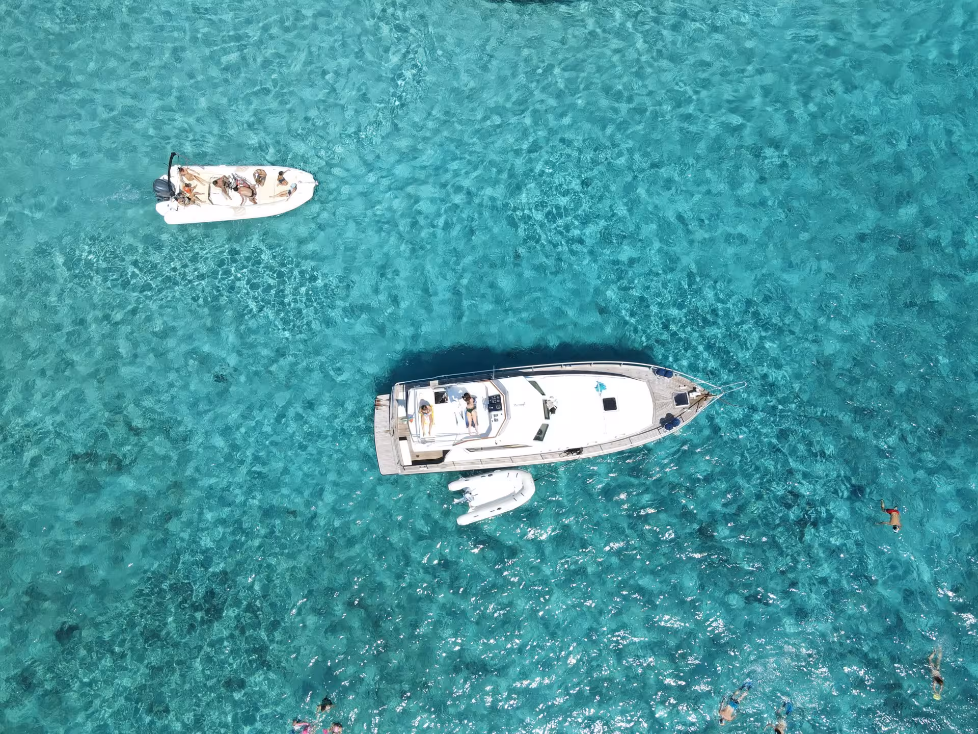 Aerial view of a luxury yacht and small boat on crystal-clear waters in La Maddalena Archipelago, perfect for a scenic boat trip.